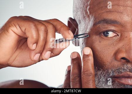 Pflege, Zoom und schwarzer Mann mit einer Pinzette zur Haarentfernung, isoliert auf Studiohintergrund. Reinigung, Schönheit und Gesicht eines afrikanischen Senior-Modells Stockfoto