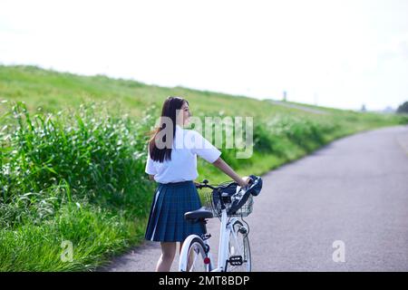 Japanische Highschool-Schülerin auf einem Fahrrad im Freien Stockfoto