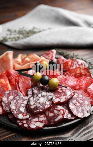 Leckere Salami und andere Delikatessen auf Holztisch, Nahaufnahme Stockfoto
