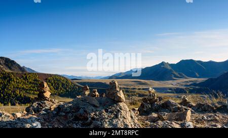 Die übereinander gestapelten Steine liegen tagsüber in Altai vor der Kulisse der Berge. Stockfoto