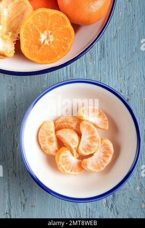 Scheiben geschälte Mandarine in einer Schüssel, Draufsicht. Nahaufnahme einer Mandarine Orange auf blauem Holzhintergrund. Stockfoto