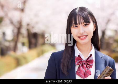 Japanisches Highschool-Porträt mit Kirschblüten in voller Blüte Stockfoto