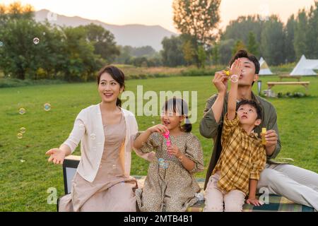 Die Familie bläst Blasen unter der untergehenden Sonne Stockfoto