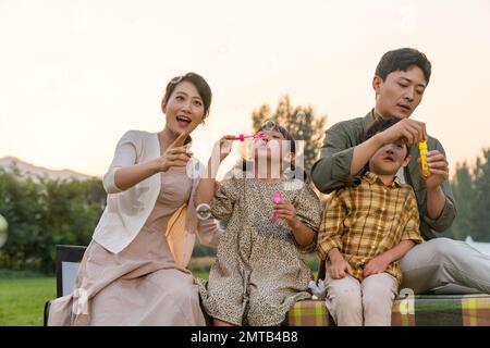 Die Familie bläst Blasen unter der untergehenden Sonne Stockfoto