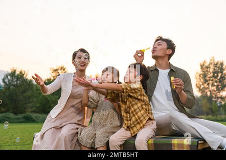 Die Familie bläst Blasen unter der untergehenden Sonne Stockfoto