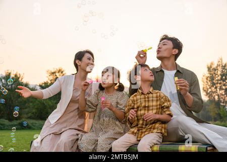 Die Familie bläst Blasen unter der untergehenden Sonne Stockfoto