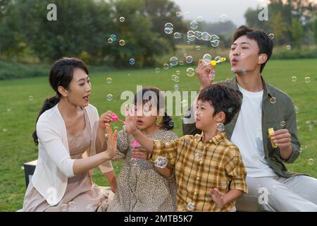 Die Familie bläst Blasen unter der untergehenden Sonne Stockfoto