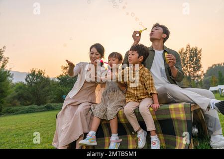 Die Familie bläst Blasen unter der untergehenden Sonne Stockfoto