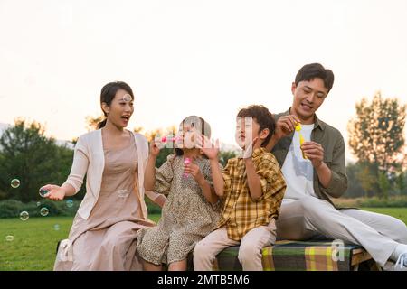 Die Familie bläst Blasen unter der untergehenden Sonne Stockfoto