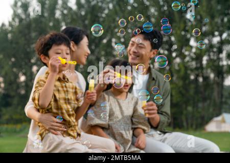 Die Familie bläst Blasen unter der untergehenden Sonne Stockfoto