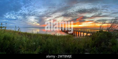 Panoramablick vom Kure Beach auf den goldenen Sonnenuntergang am Horizont in North Carolina Stockfoto