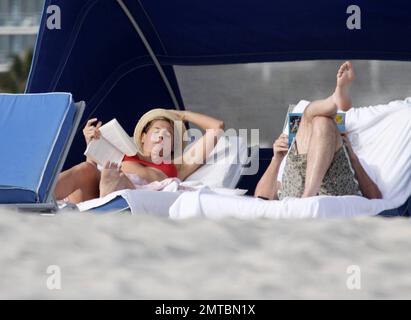 EXKLUSIV!! "America's Got Talent" Richter Piers Morgan und seine Autorin-Freundin Celia Walden entspannen sich zusammen in Miami Beach. Morgan genoss einige Ruhezeiten und schien in die Autobiografie von Michael VaughanÕs vertieft zu sein, Zeit, um sich zu erklären, während seine atemberaubende Freundin sich in einem roten Bikini sonnte. Miami, FL 1/14/2010 . Stockfoto