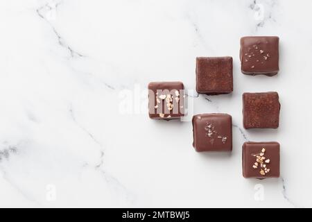 Schokoladenbonbons auf weißem Marmorhintergrund, Blick von oben mit Kopierraum Stockfoto