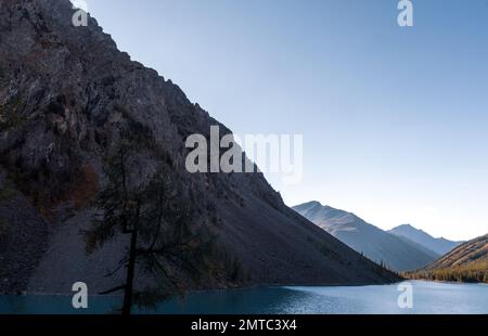 Ein kleiner Fluss in der Ferne zwischen den Bergen fließt von den schneebedeckten Gletschern von den Felsen herunter. Stockfoto