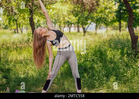 Yoga Frau auf grünem Gras Mädchen entspannt auf dem Feld. Yoga Frau im grünen Park Mädchen tun Gymnastik im Freien. Meditierende Frau in Meditation im Yoga p Stockfoto