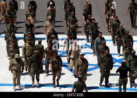 Supporters of Iraqi Hezbollah brigades marching in military uniforms ...