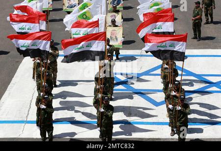 Supporters of Iraqi Hezbollah brigades marching in military uniforms ...