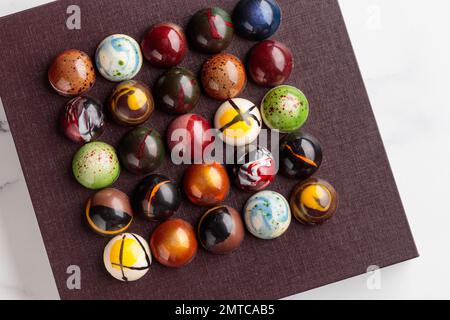 Auswahl an handgefertigten Schokoladenbonbons. Köstliches Dessert auf einem weißen Marmorbanner Stockfoto