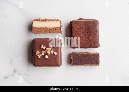 Handgefertigte Schokoladen-Bonbons und geschnittene Stücke Süßigkeiten mit Pralinen und Trüffeln auf weißem Hintergrund mit horizontalem Foto im Kopierraum Stockfoto