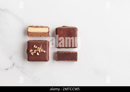 Handgefertigte Schokoladen-Bonbons und geschnittene Stücke Süßigkeiten mit Pralinen und Trüffeln auf weißem Hintergrund mit horizontalem Foto im Kopierraum Stockfoto