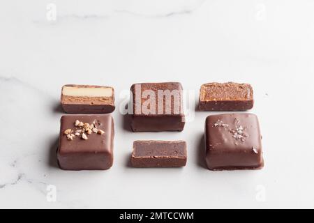 Handgefertigte Schokoladen-Bonbons und geschnittene Stücke Süßigkeiten mit Pralinen und Trüffeln auf weißem Hintergrund mit horizontalem Foto im Kopierraum Stockfoto