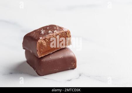 Handgefertigte Schokoladen-Bonbons und geschnittene Stücke Süßigkeiten mit Pralinen und Trüffeln auf weißem Hintergrund mit horizontalem Foto im Kopierraum Stockfoto