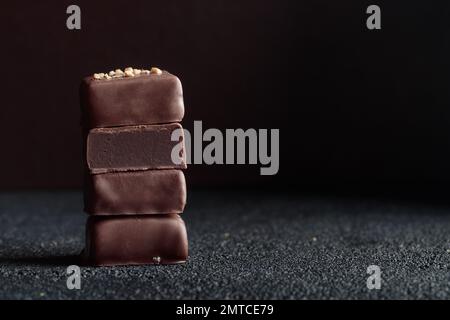 Handgefertigte Schokoladen-Bonbons und geschnittenes Stück Süßigkeiten mit Trüffel auf schwarzem Hintergrund mit horizontalem Foto im Kopierraum Stockfoto