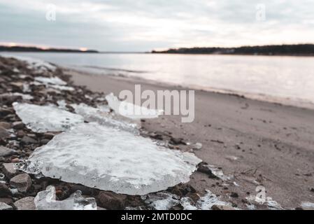 Kleine Gletscher des ersten Eisens liegen im Herbst bei Sonnenaufgang am Sandstrand in der Nähe des Flusses Vilyui in Yakutia Stockfoto