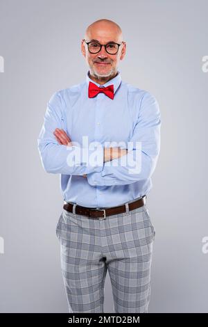 Nahaufnahme eines Mannes mittleren Alters mit Hemd und Fliege, während er auf isoliertem grauen Hintergrund steht. Speicherplatz kopieren. Stockfoto