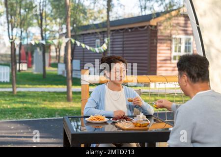 Paare mittleren Alters auf dem Campingplatz plaudern bei einer Tasse Tee Stockfoto
