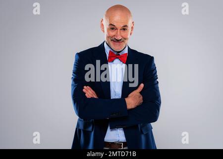 Studioporträt eines Mannes mittleren Alters mit Fliege und Blazer, während er auf einem isolierten grauen Hintergrund steht. Speicherplatz kopieren. Stockfoto