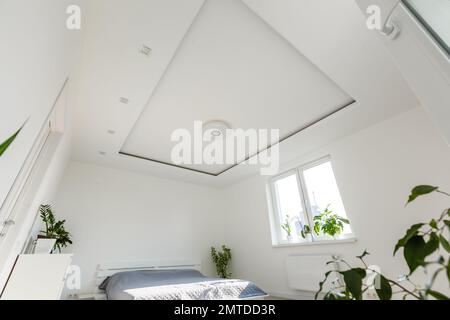 Abstrakter weißer wellenförmiger Vorhang im weißen Schlafzimmer-Apartment Stockfoto