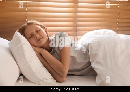 Süßes, junges Mädchen, das im Bett am Fenster schläft Stockfoto