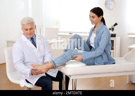 Die Einlegesohle des männlichen Orthopäden am Fuss des Patienten in der Klinik Stockfoto