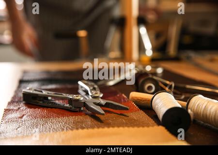 Werkzeuge für Lederarbeiten am Schreibtisch in der Werkstatt Stockfoto