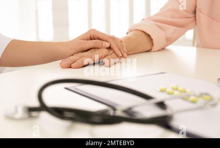 Doktor hält die Hand eines älteren Patienten in der Praxis, Nahaufnahme Stockfoto