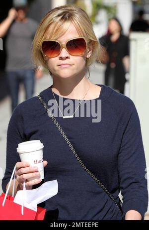 An einem sonnigen Nachmittag ging die Schauspielerin Reese Witherspoon in einem mehrstufigen Rock mit Blumenmuster und Pullover hinaus, um sich einen Kaffee und Schweizer Schokolade vom Chocolatier Teuscher zu holen. Die zarte Halskette, die Reese trug, ist eine liebevolle Erinnerung an ihre Kinder, da sie „Ava“ und „Deacon“ heißt. Los Angeles, Kalifornien. 03/08/11. Stockfoto