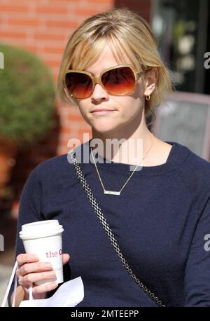 An einem sonnigen Nachmittag ging die Schauspielerin Reese Witherspoon in einem mehrstufigen Rock mit Blumenmuster und Pullover hinaus, um sich einen Kaffee und Schweizer Schokolade vom Chocolatier Teuscher zu holen. Die zarte Halskette, die Reese trug, ist eine liebevolle Erinnerung an ihre Kinder, da sie „Ava“ und „Deacon“ heißt. Los Angeles, Kalifornien. 03/08/11. Stockfoto