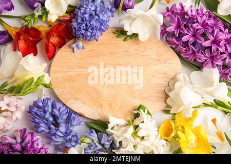 Wunderschöne Frühlingsblumen und Holzbrett auf weißem Hintergrund, flach liegend. Platz für Text Stockfoto