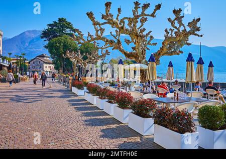 ASCONA, SCHWEIZ - 28. MÄRZ 2022: Die wunderschönen Terrassen der Cafés und Restaurants im Freien am Ufer des Lago Maggiore auf der Piazza Giuseppe Mott Stockfoto