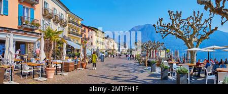 Gehen Sie die Piazza Giuseppe Motta mit bunten Oldtimer-Häusern, Cafés, Bars, Souvenirläden und einem Blick auf den Lago Maggiore, Ascona, Schweiz hinunter Stockfoto