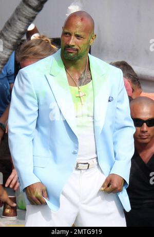 EXKLUSIV!! Er trägt eine blaue Babyjacke, ein weißes Hemd, weiße Hosen, weiße Schuhe, eine Kette mit Kruzifix und etwas, das wie ein grüner Glibber auf Gesicht und Brust aussieht. Dwayne „The Rock“ Johnson wird zusammen mit seinem Stunt-Double am Set gesehen, wie er eine Actionszene für seinen neuen Film „Pain & Gain“ dreht. Der Film wird von „Transformers“ Regisseur Michael Bay gedreht und soll 2013 veröffentlicht werden. Maimi, Florida 14. April 2012 Stockfoto