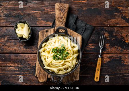 Deutsche Spaetzle-Eiernudeln mit Butter und Petersilie in einer Pfanne. Holzhintergrund. Draufsicht. Stockfoto