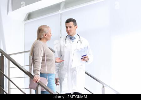 Arzt und Patient diskutieren Diagnose auf Treppen im Krankenhaus Stockfoto