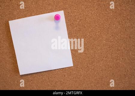 Weißer, leerer Aufkleber, der an einer Korktafel in einem Büro befestigt ist Stockfoto