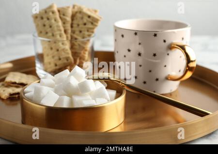 Raffinierte Zuckerwürfel in der Schüssel und aromatischer Tee auf dem Tisch Stockfoto