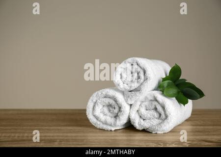 Gerollte Handtücher und grüner Ast auf Holztisch reinigen. Platz für Text Stockfoto