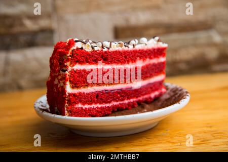 Ein roter Samtkuchen ist ein Schokoladenkuchen mit einer tiefroten oder leuchtend roten Farbe. Er wird in der Regel als mehrschichtiger Kuchen zubereitet, der mit einer Frischkäse-Glasur oder bedeckt ist Stockfoto