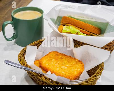 Nahaufnahme von Schinken- und Ei-Sandwich mit Kaffee und Hash Brown in Taipei, Taiwan Stockfoto