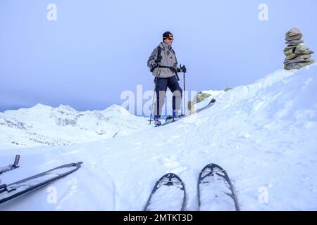 Skifahrer erreichen den Gipfel eines Berges. Schweizer Alpen Stockfoto